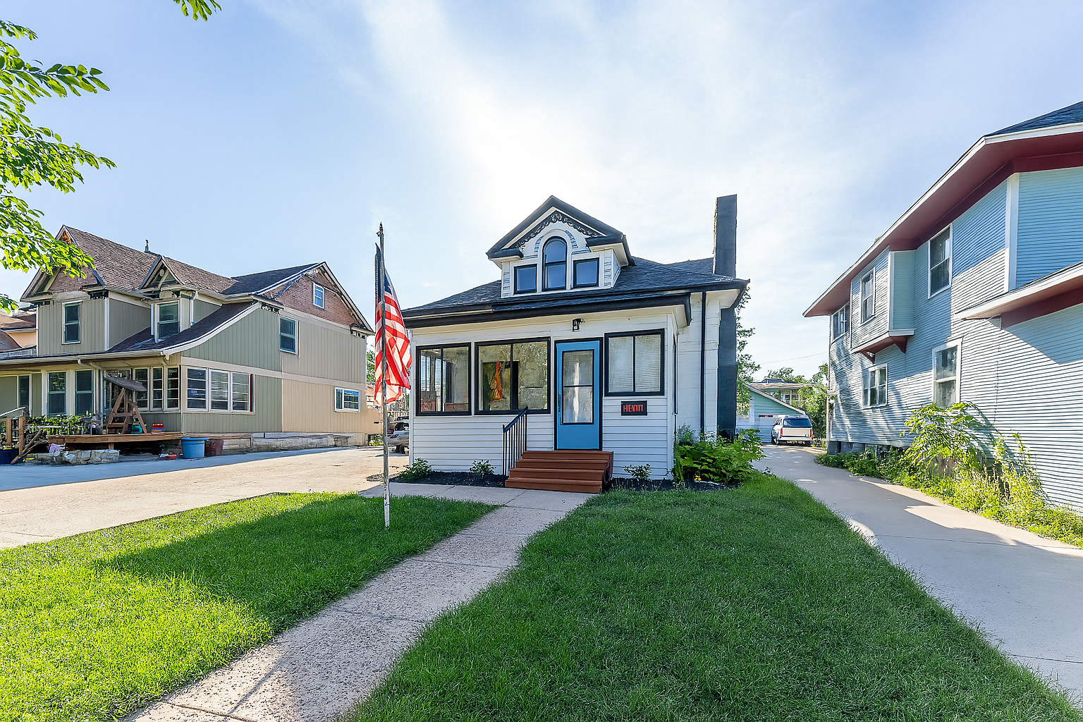 A quaint Cape Cod-style home with beige siding and white window frames, nestled among mature trees in a lush green lawn, located at 2201 S Euclid Ave, Sioux Falls, SD.