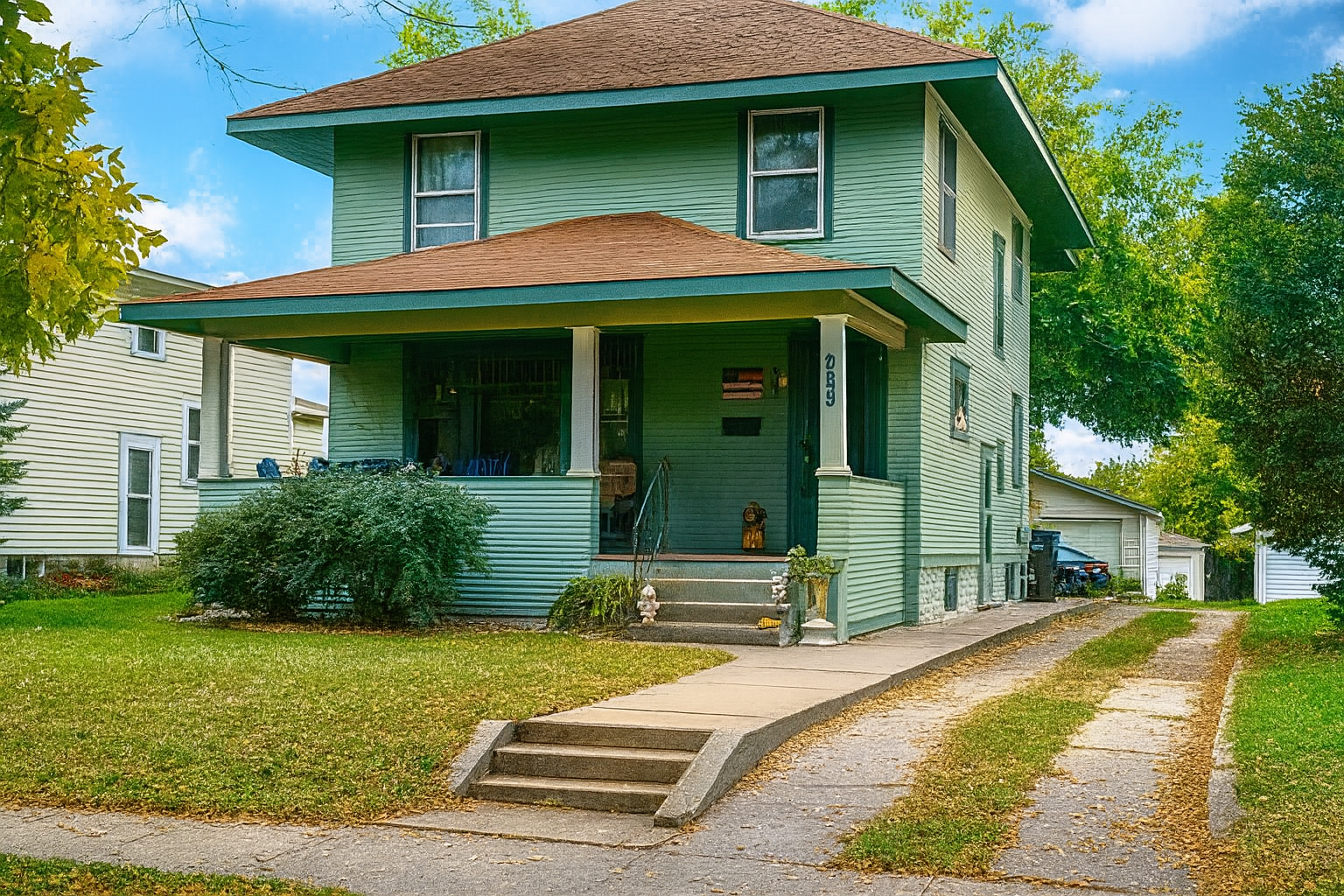 A quaint Cape Cod-style home with beige siding and white window frames, nestled among mature trees in a lush green lawn, located at 2201 S Euclid Ave, Sioux Falls, SD.