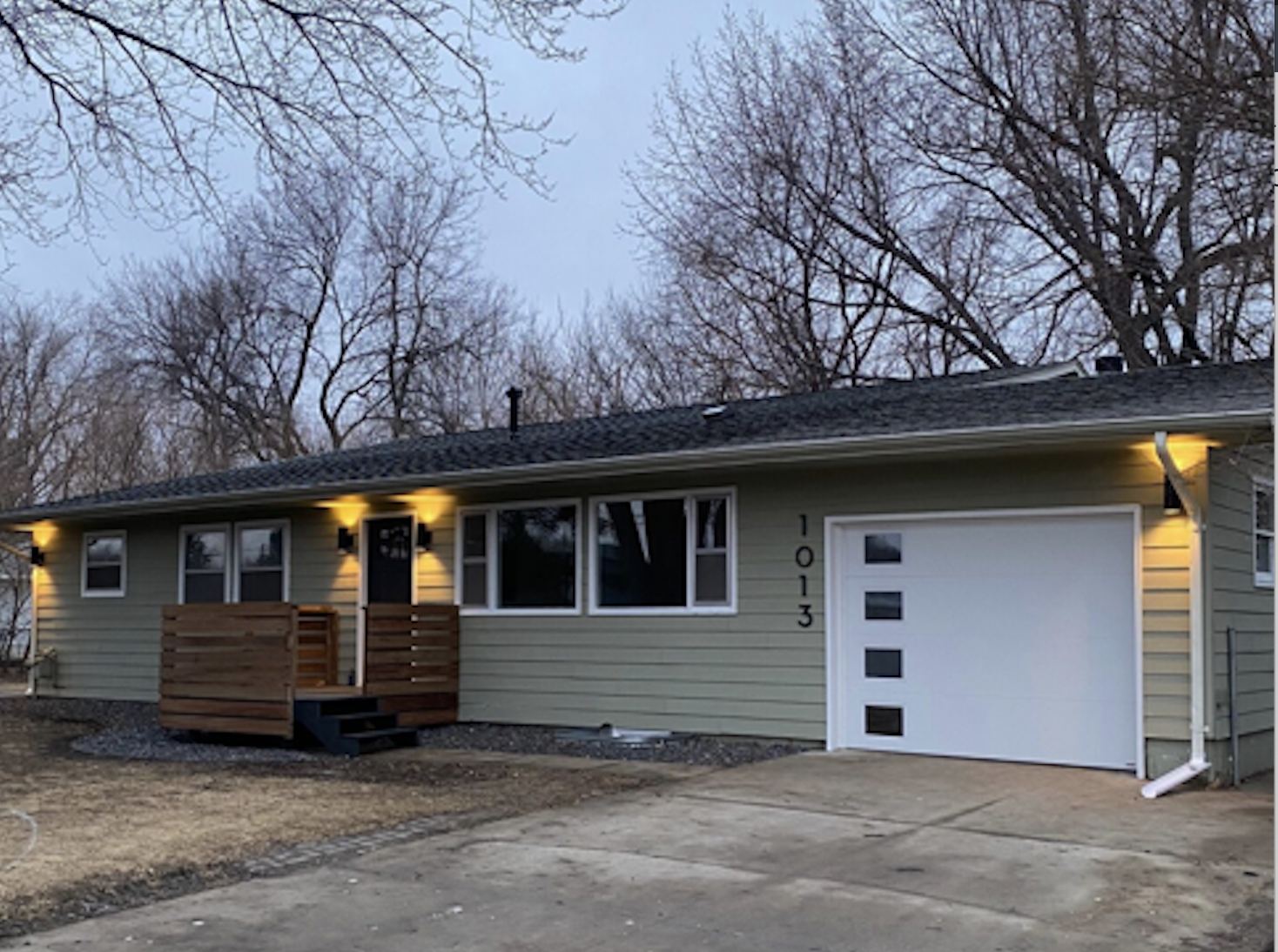 A quaint Cape Cod-style home with beige siding and white window frames, nestled among mature trees in a lush green lawn, located at 2201 S Euclid Ave, Sioux Falls, SD.