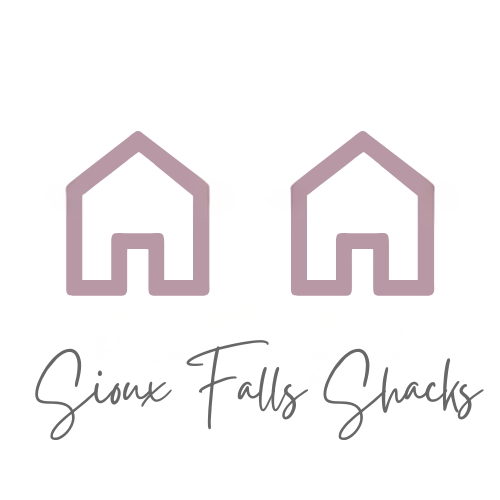 SFS A quaint Cape Cod-style home with beige siding and white window frames, nestled among mature trees in a lush green lawn, located at 2201 S Euclid Ave, Sioux Falls, SD.